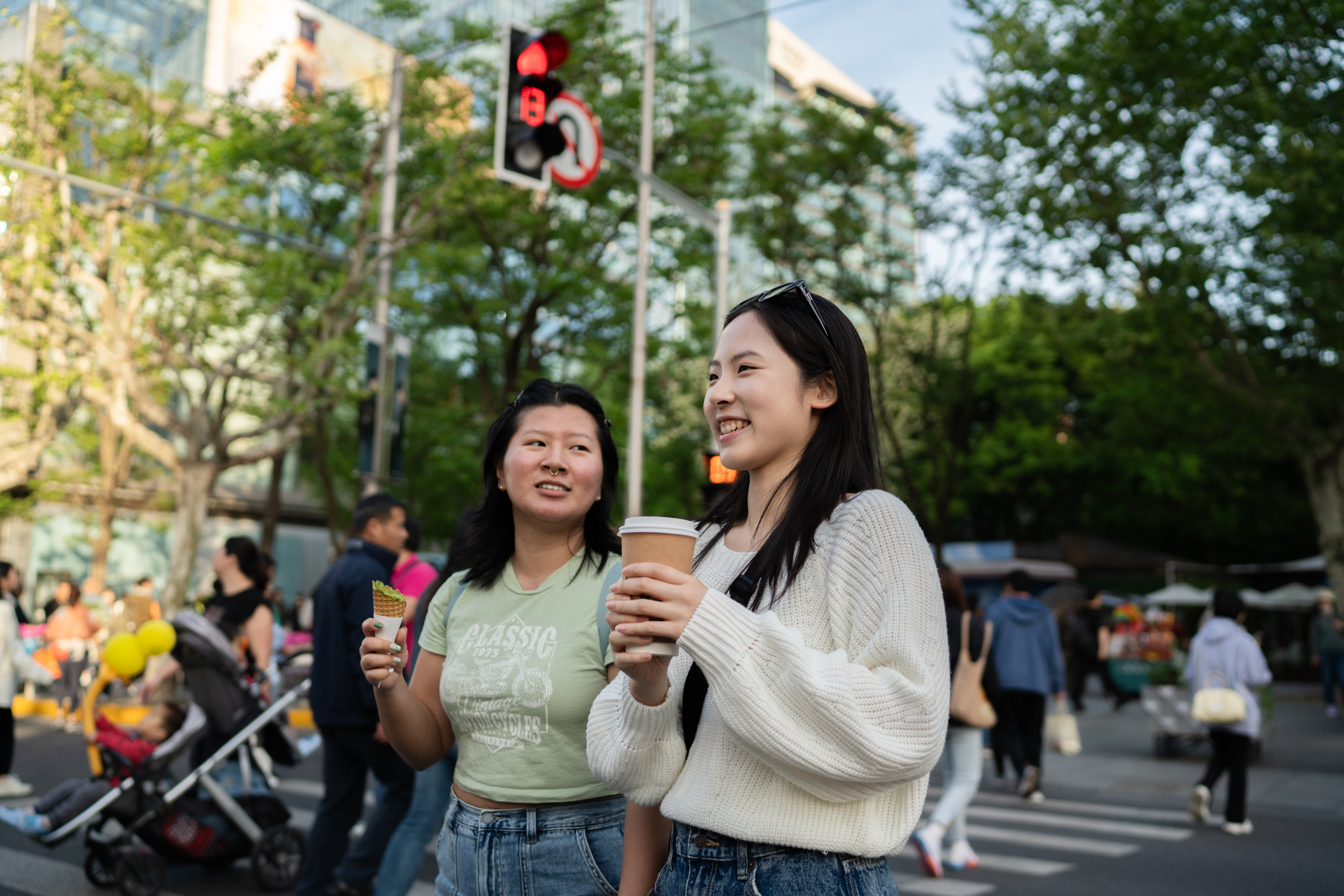 Two students with coffee and desserts on a street in Shanghai.