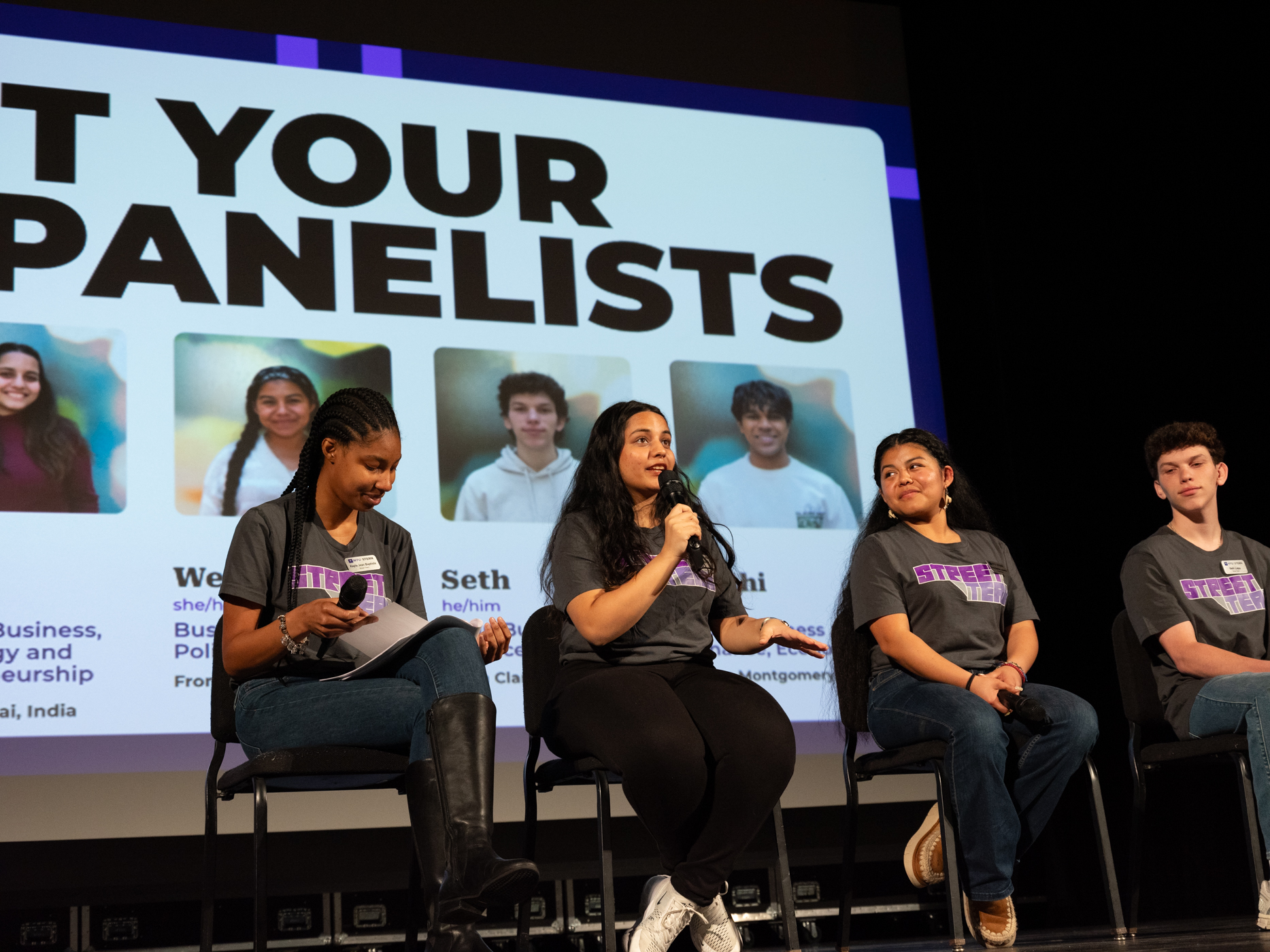 Wendy and three other students speaking on stage at a panelists discussion.