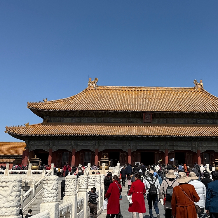 Crowds of visitors approach a large traditional Chinese building.