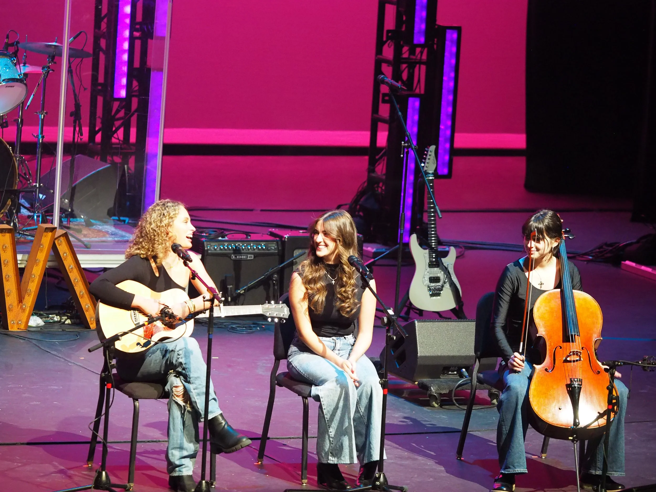 A group of students performing on stage with instruments.