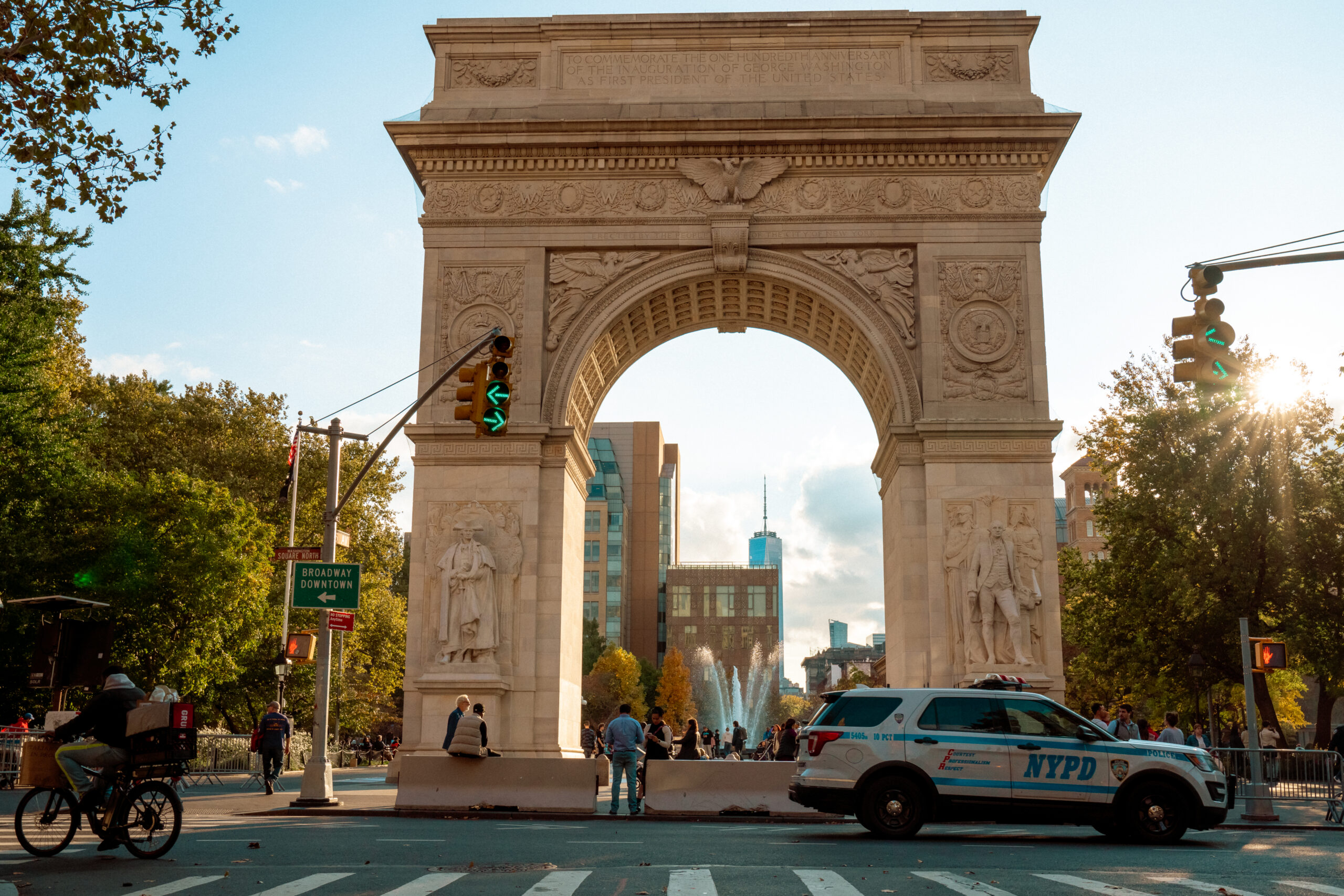 The Washington Square Arch with pedestrians and cars passing by.