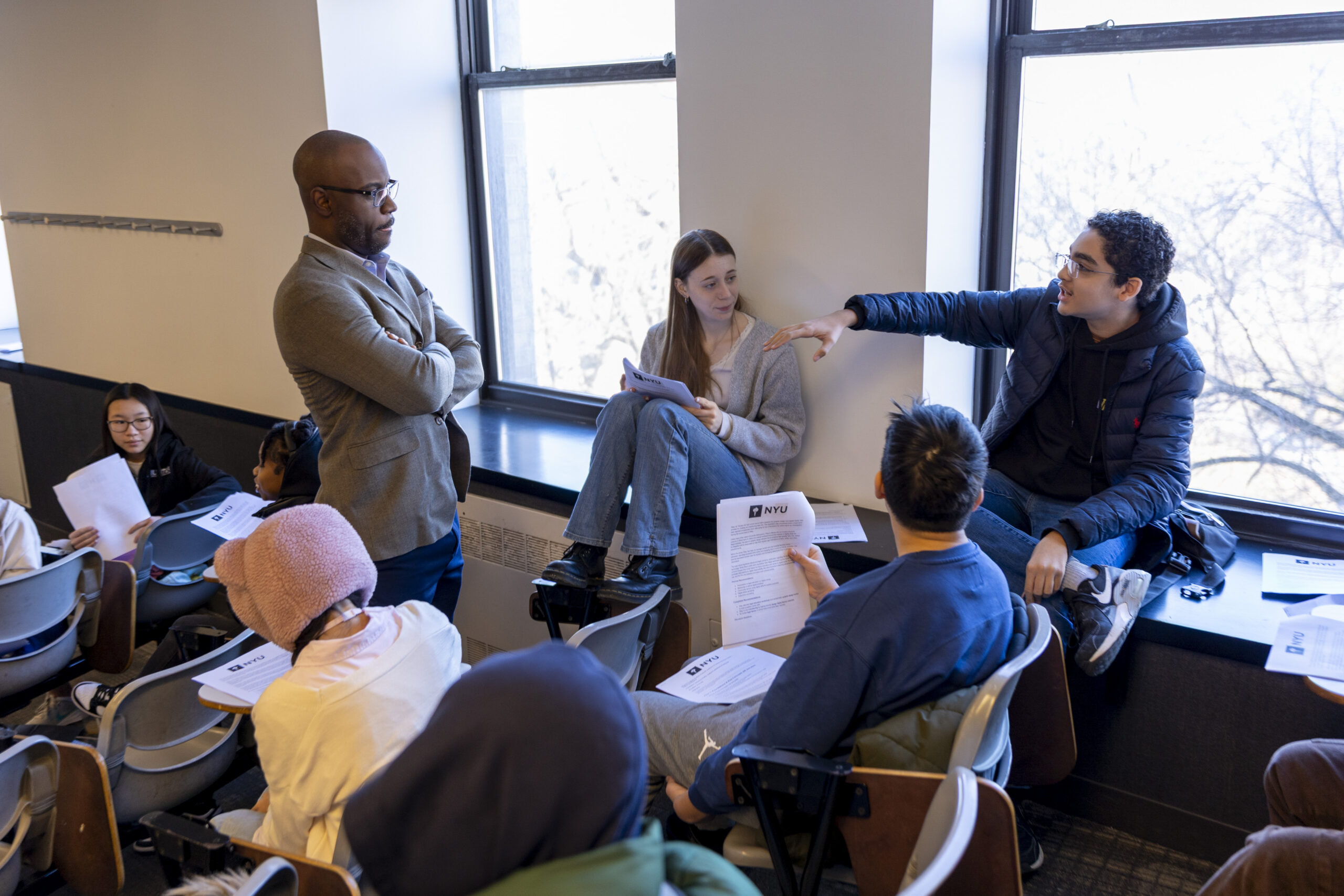 A group of students and a professor have a discussion in class.