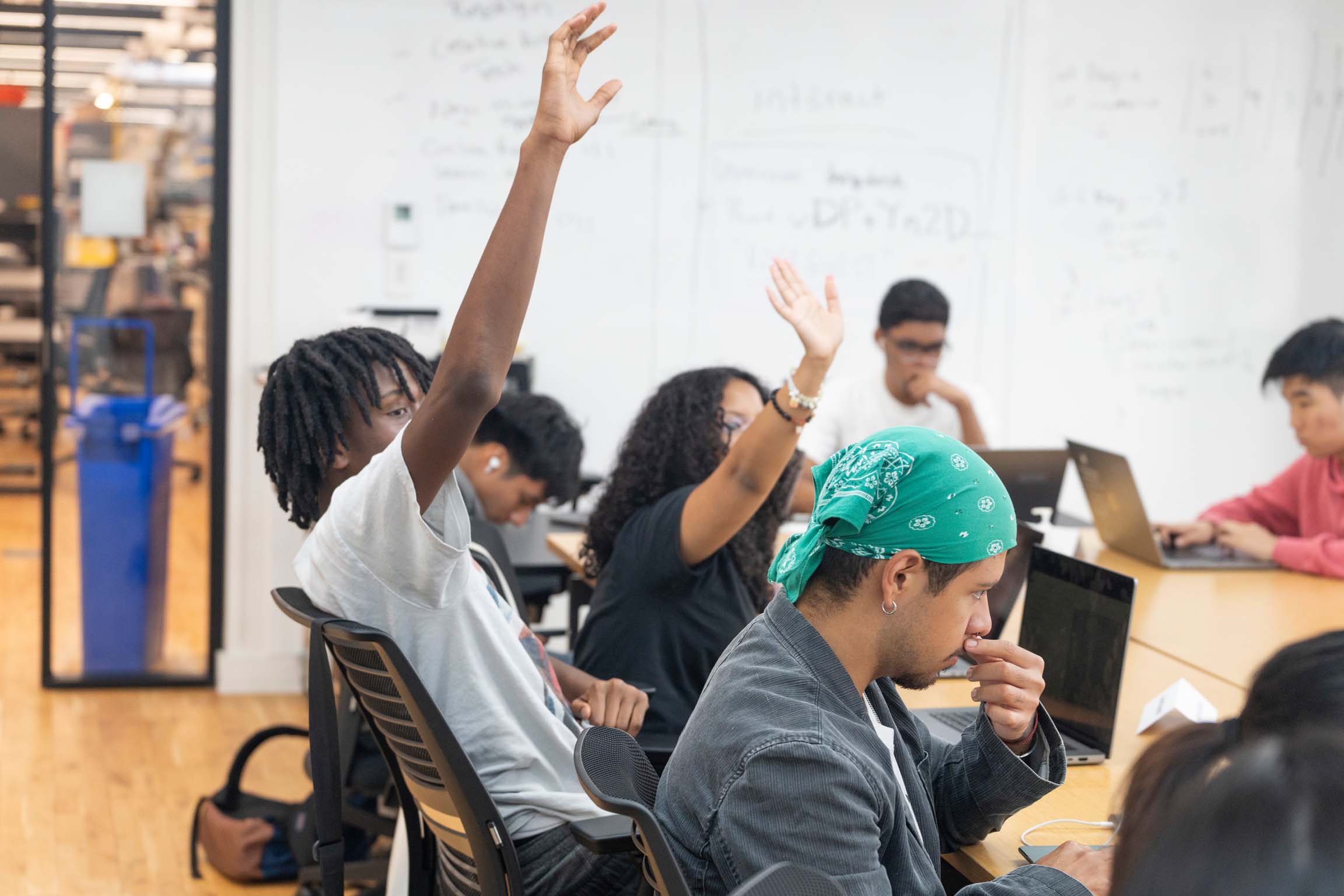 A group of students raising their hands and participating in class.