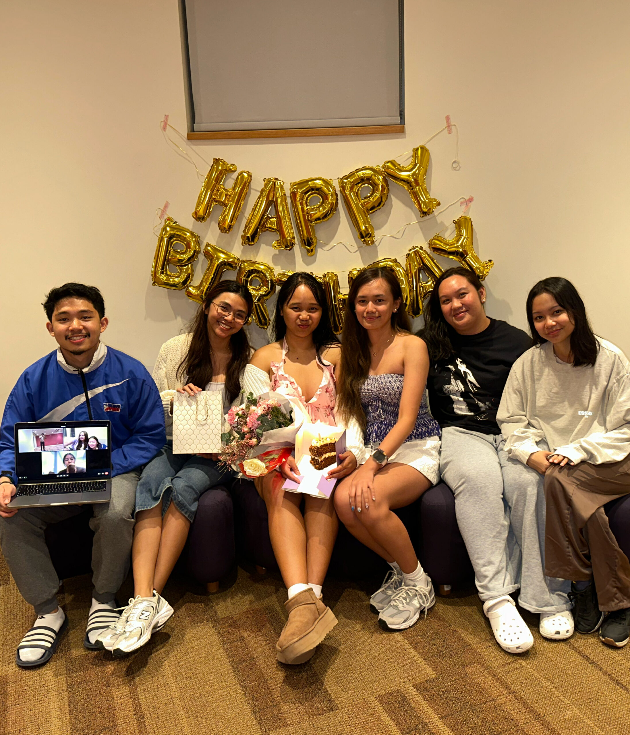 Brettany celebrates her birthday with friends. A balloon sign behind them reads 