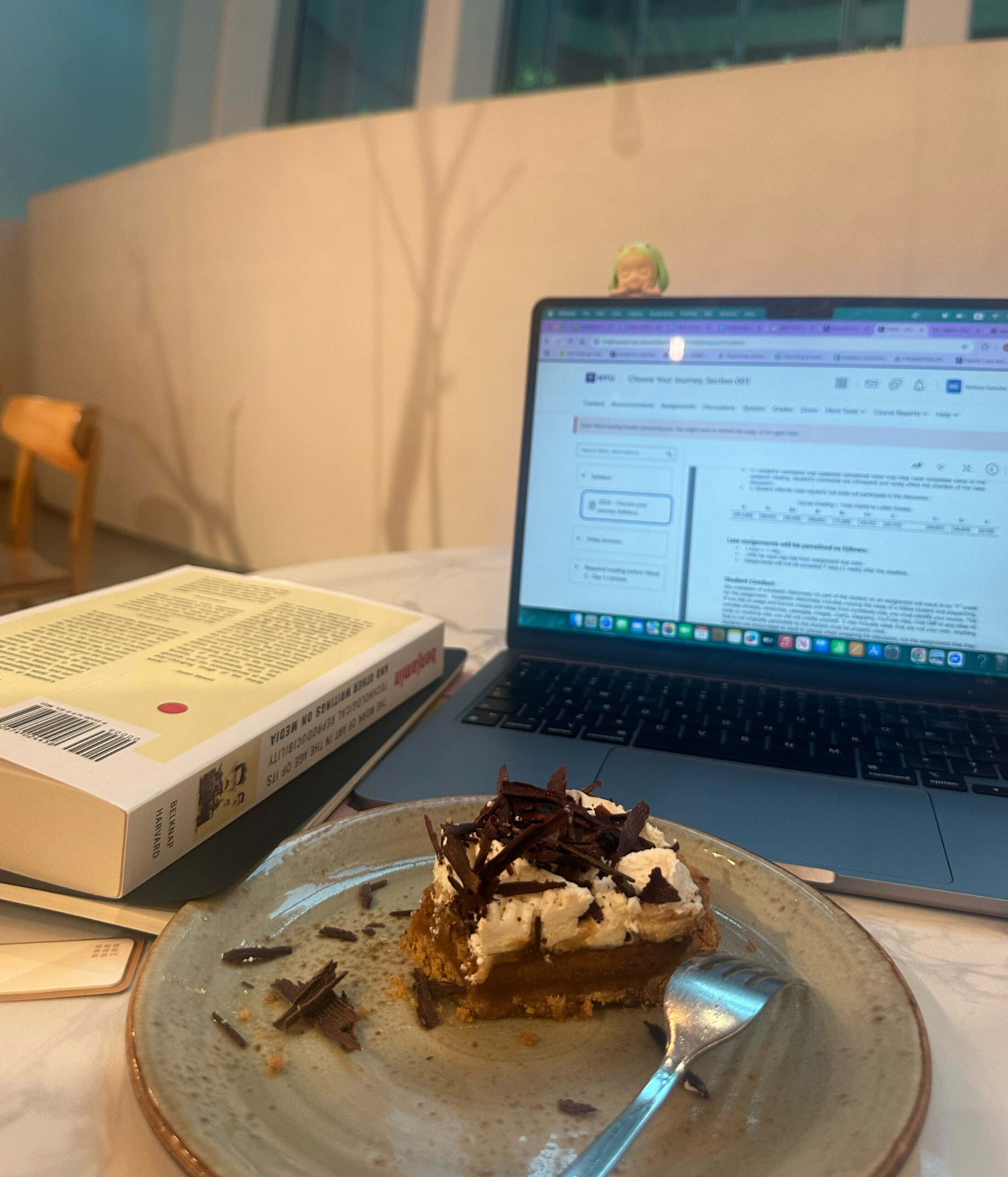 A plate with a slice of pie sits next to a laptop.
