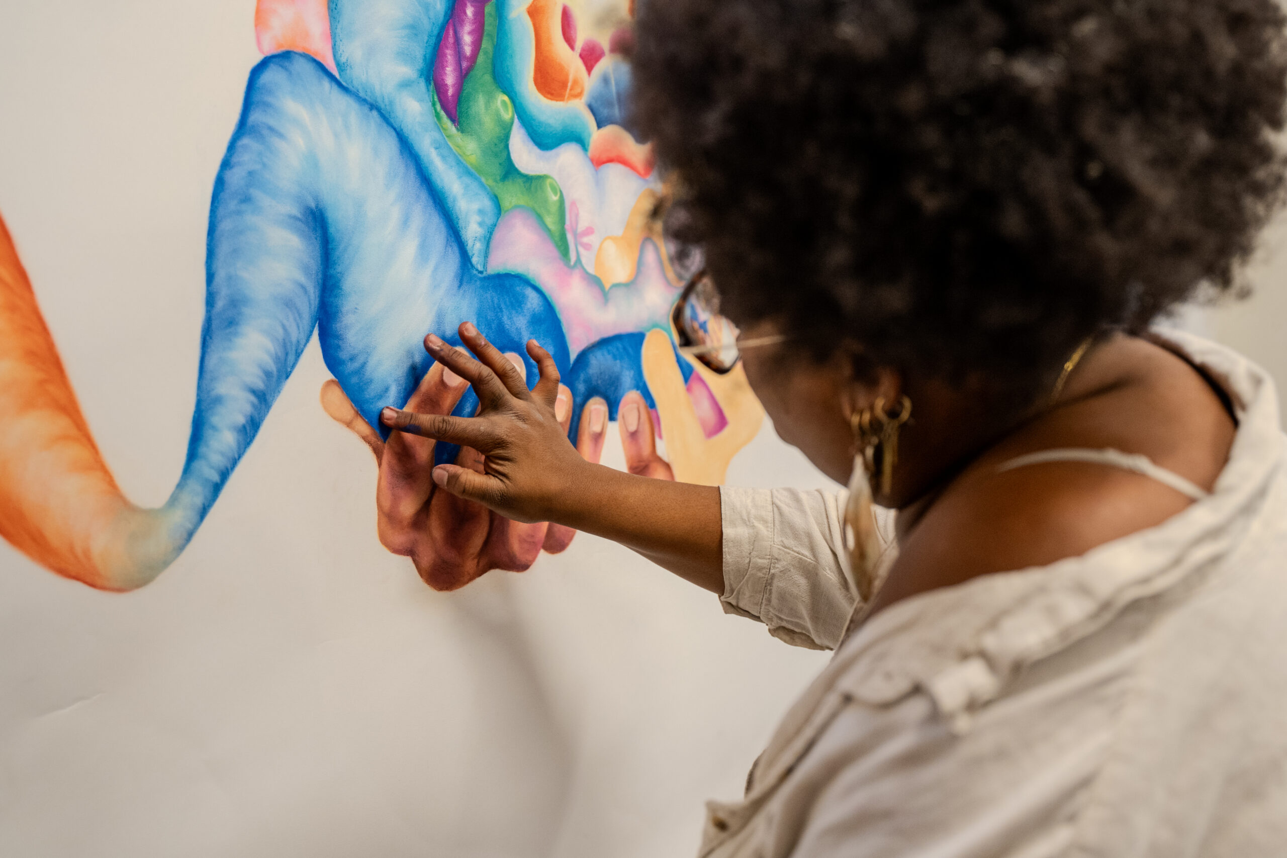 A student drawing a colorful illustration on canvas.