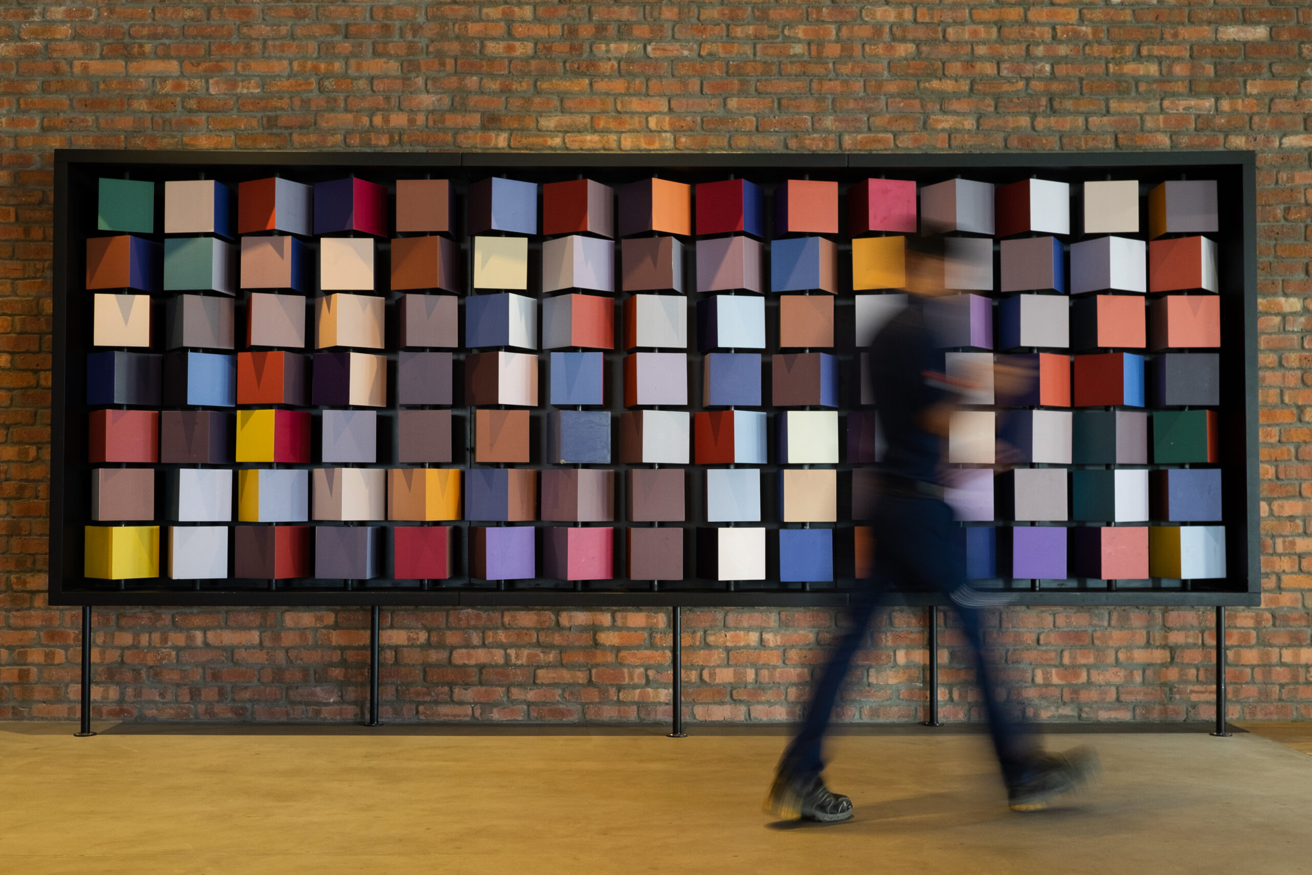 A student walking past a colorful piece of installation art.