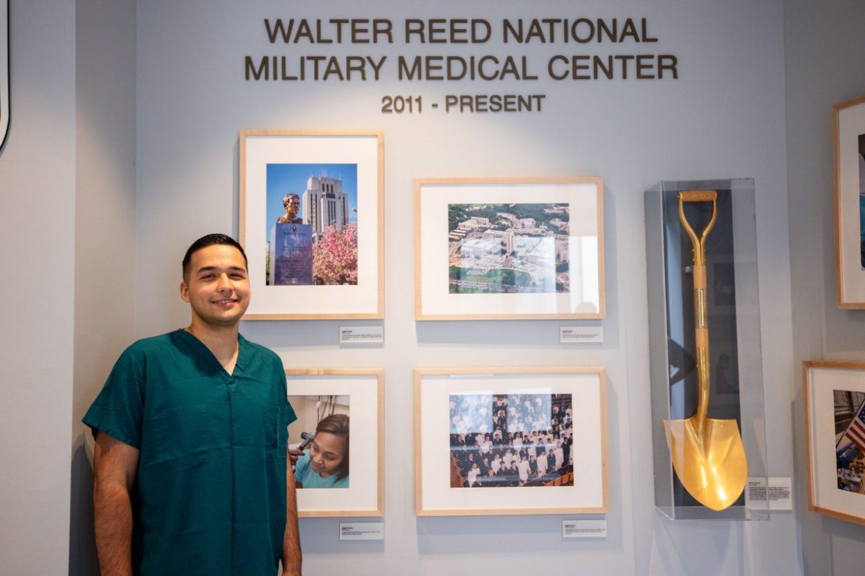 Massimo stands in front of the Walter Reed sign and history wall.