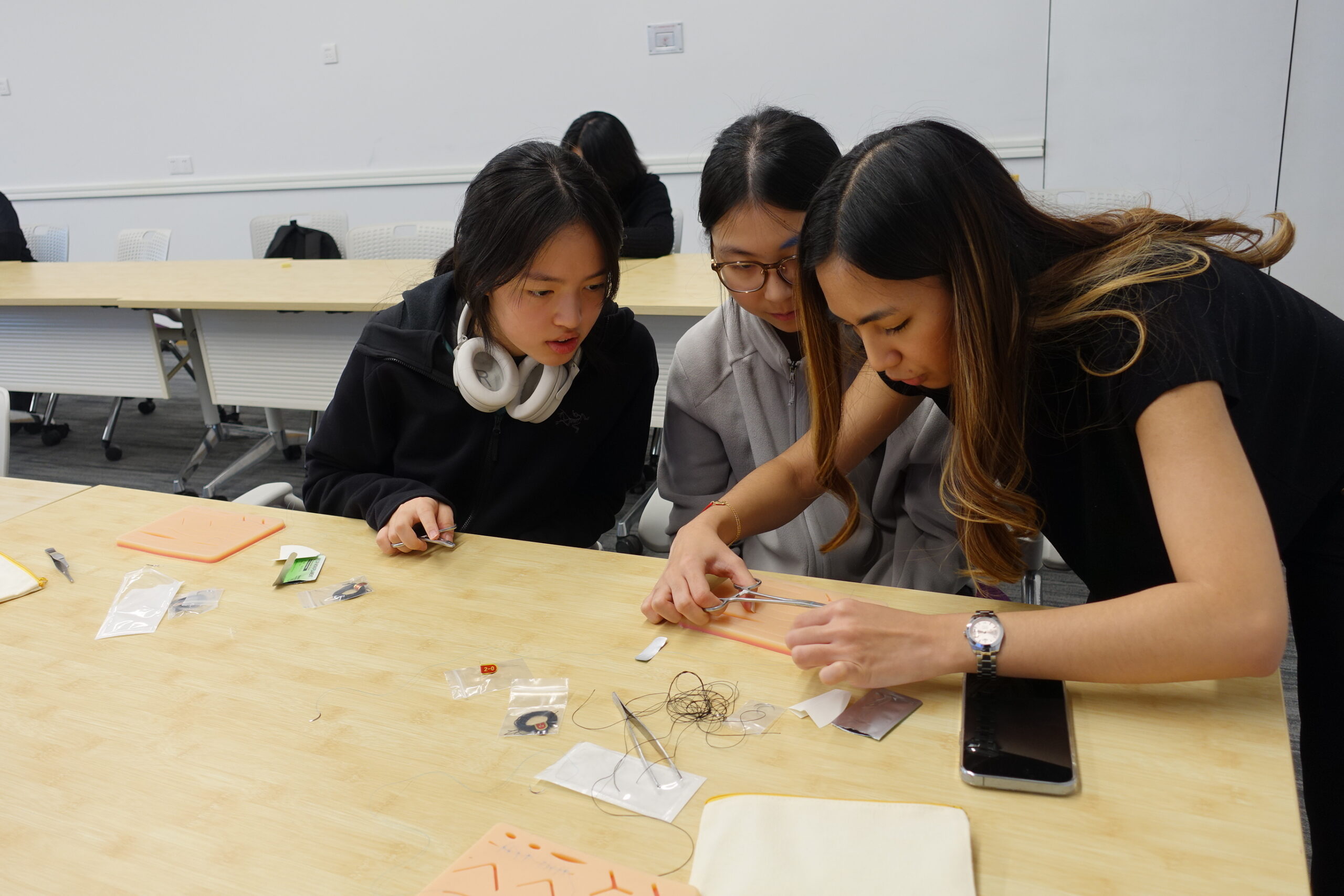 Students practice sutures together in a workshop.