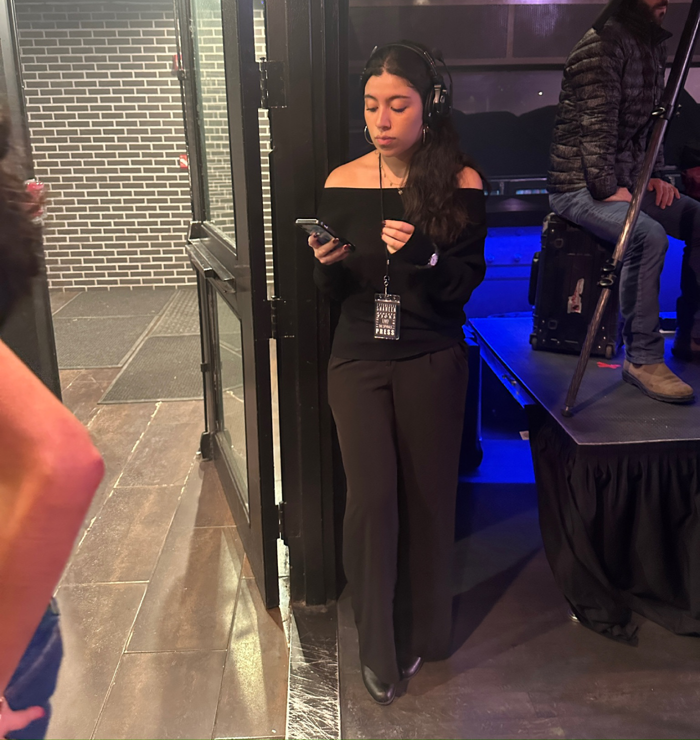 Daniella Leonzo standing backstage at NYFW, answering messages on her phone.