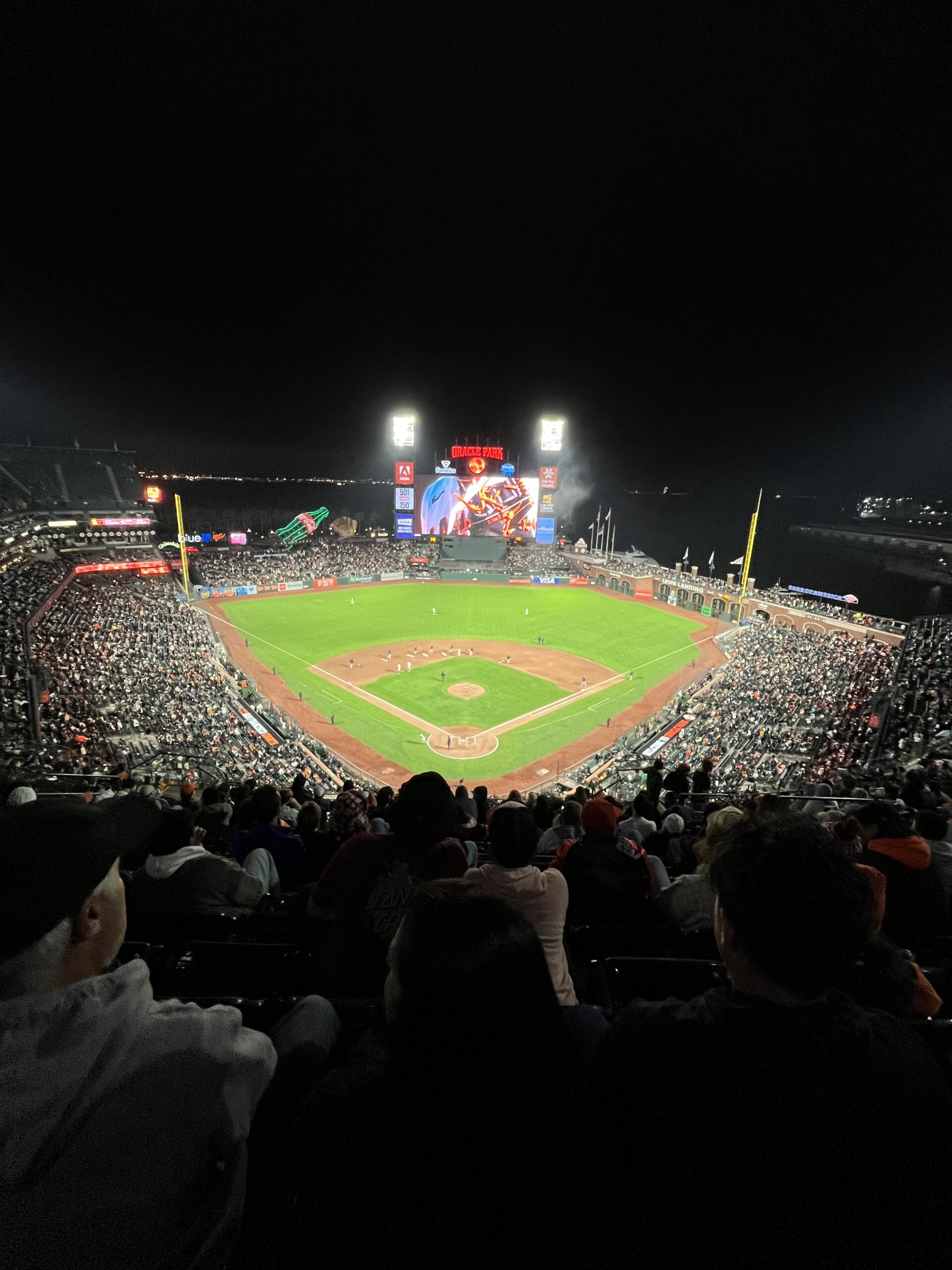 Birdseye view of Oracle Park in San Francisco. Nighttime, with bright, white lights over the stadium.