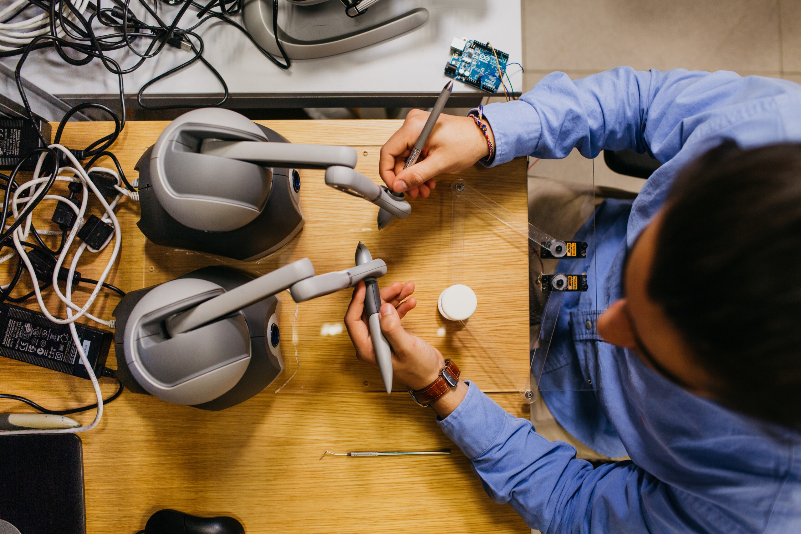 Overhead view of a student working with robotic arm devices and electronic equipment at a workstation.