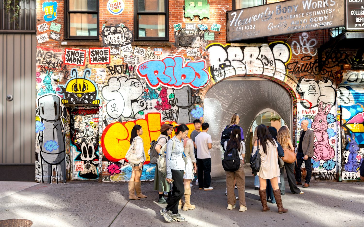Students and a professor standing in front of a graffiti wall.