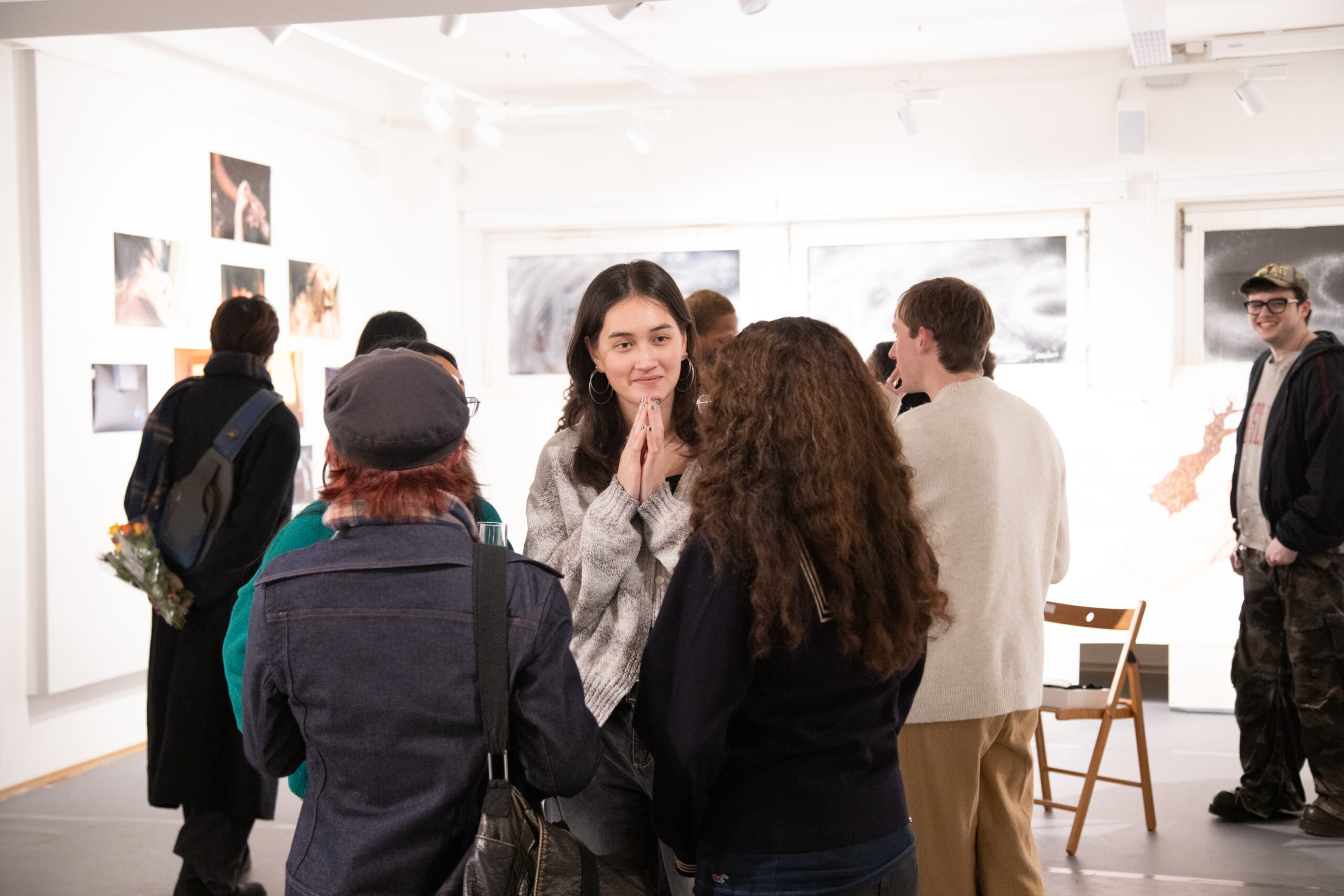 Students talking and viewing artwork in a bright gallery space during an exhibition.