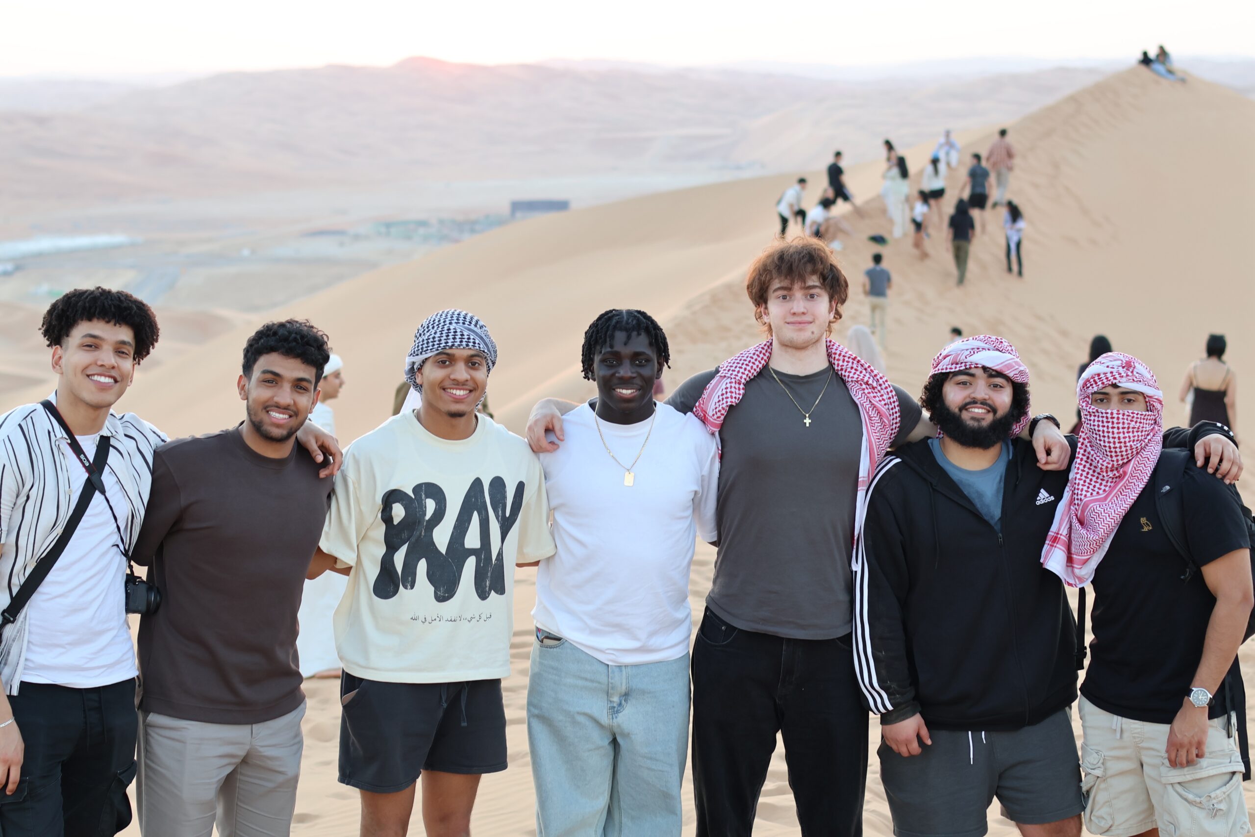 Saif posing with some friends on a sand dune at sunset.