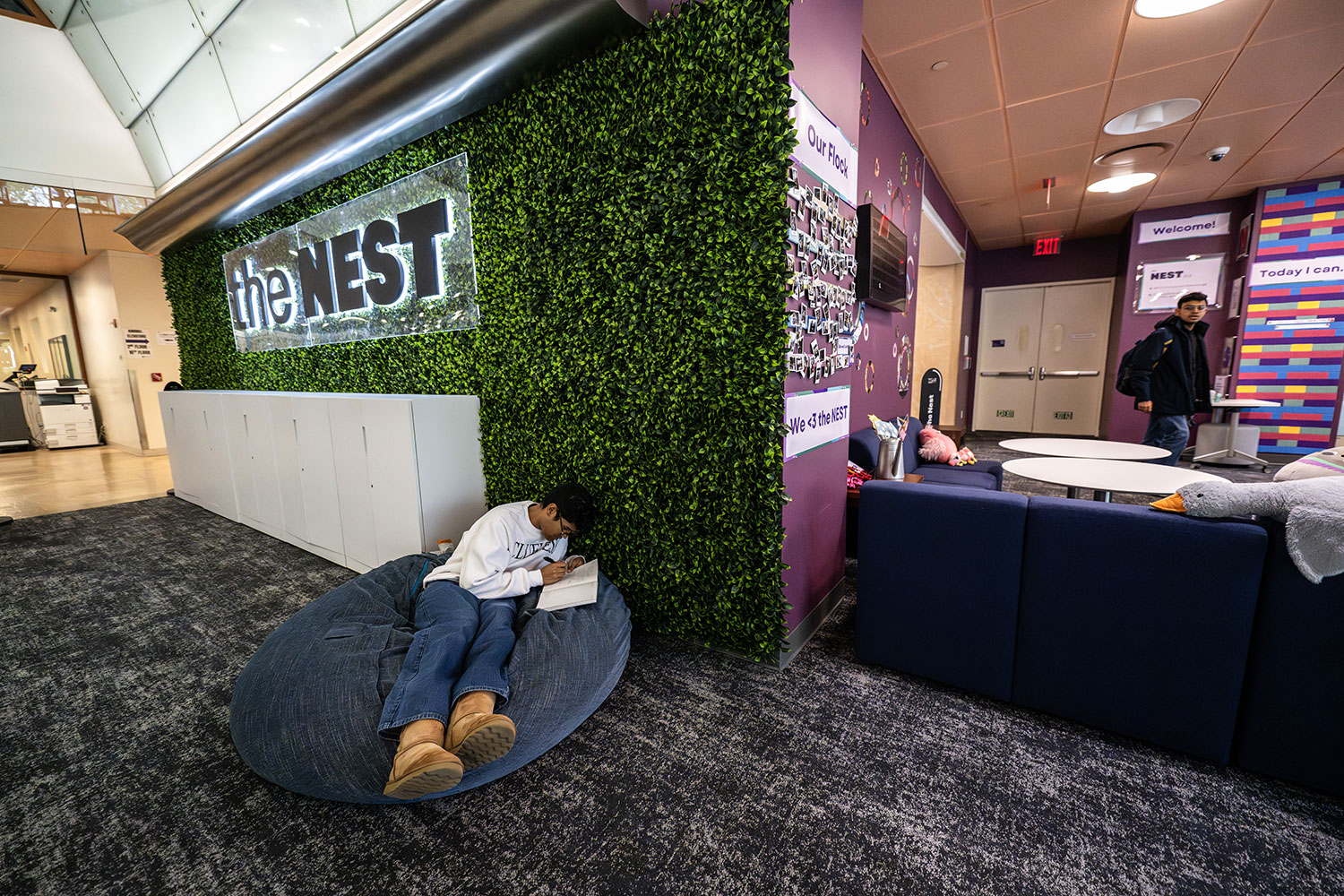 Student relaxes on a large beanbag chair while studying in a colorful campus lounge.