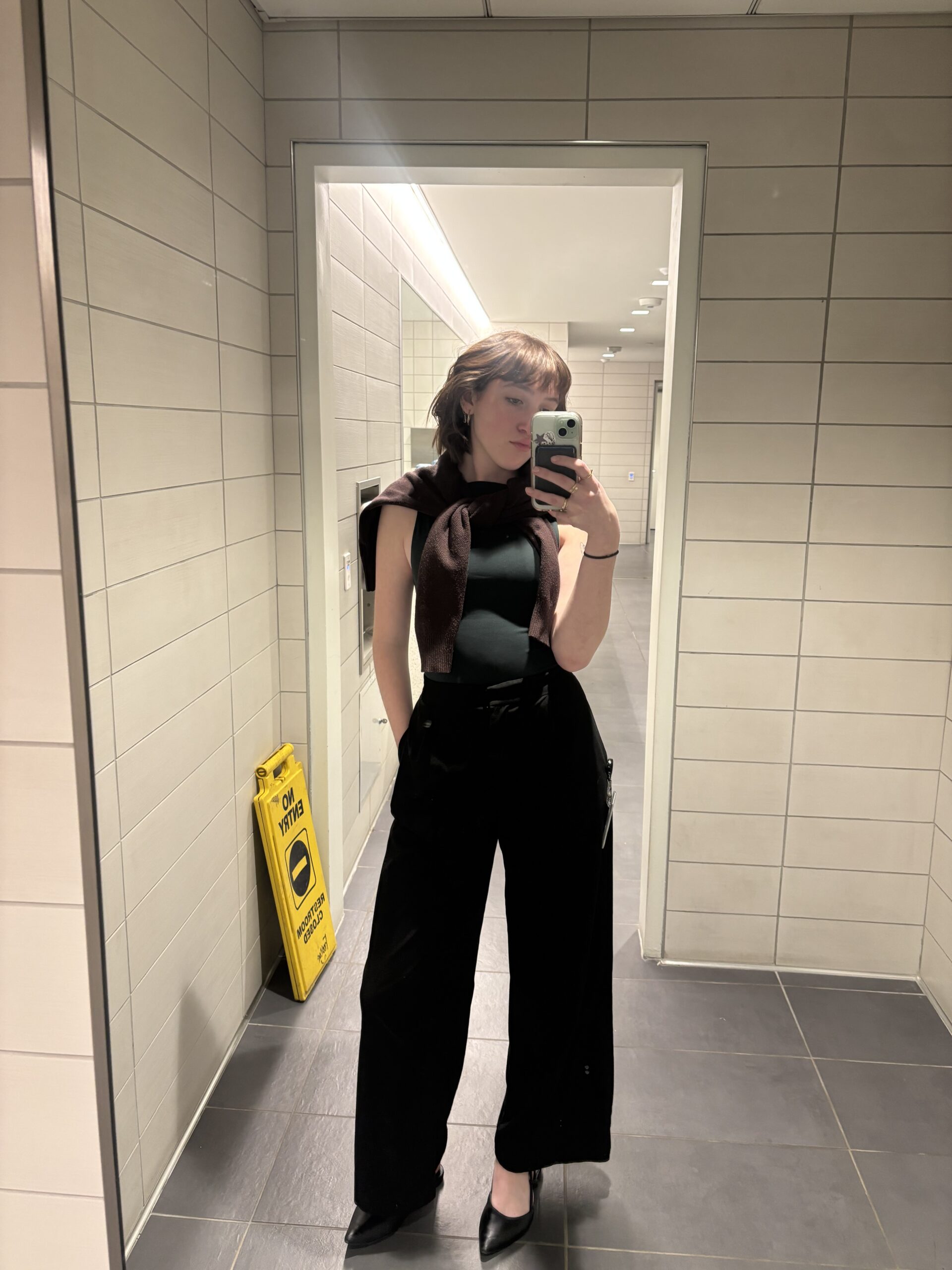 girl in mirror wearing green top and black pants