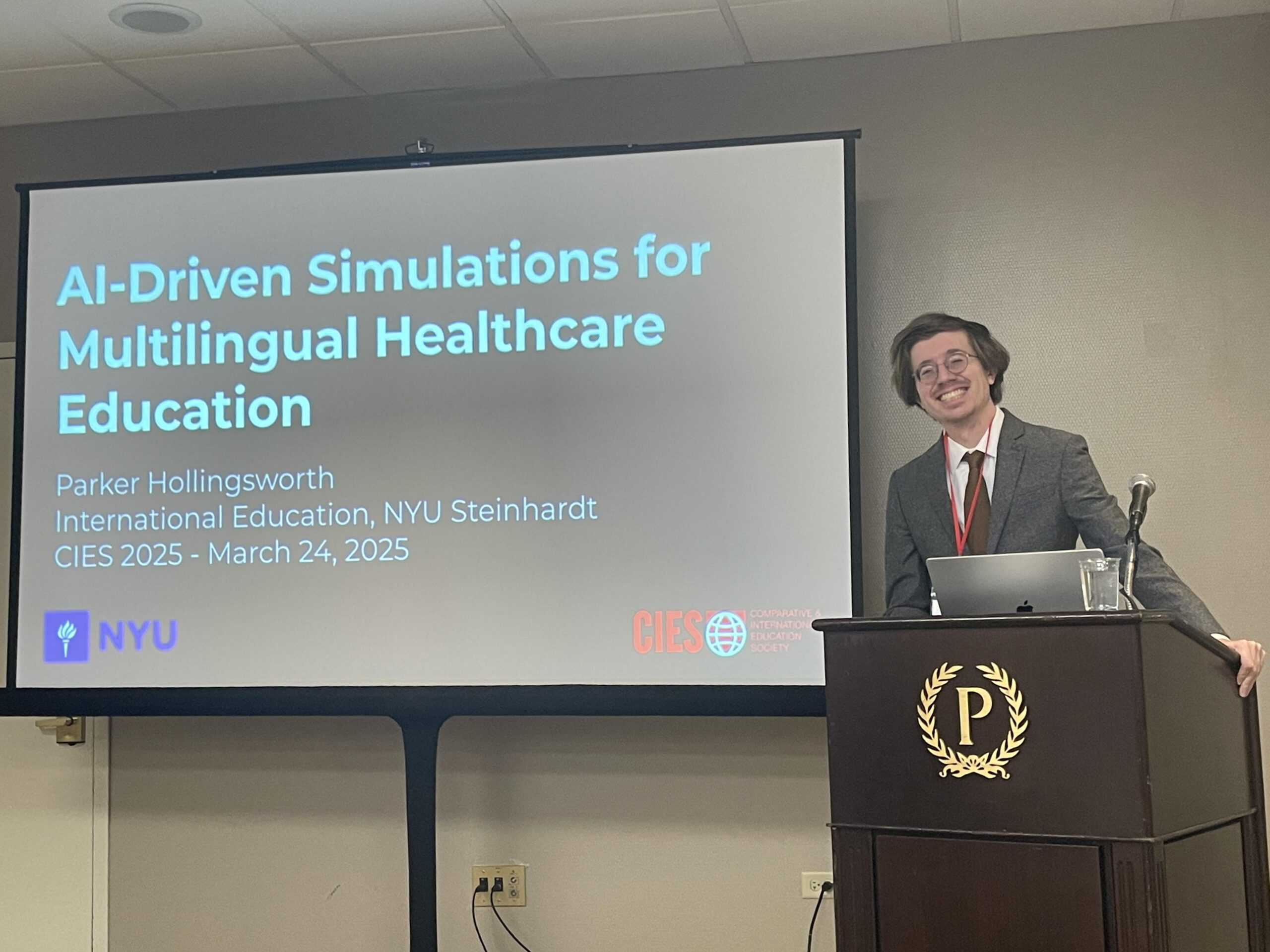 Parker stands at a podium, smiling beside a presentation slide.