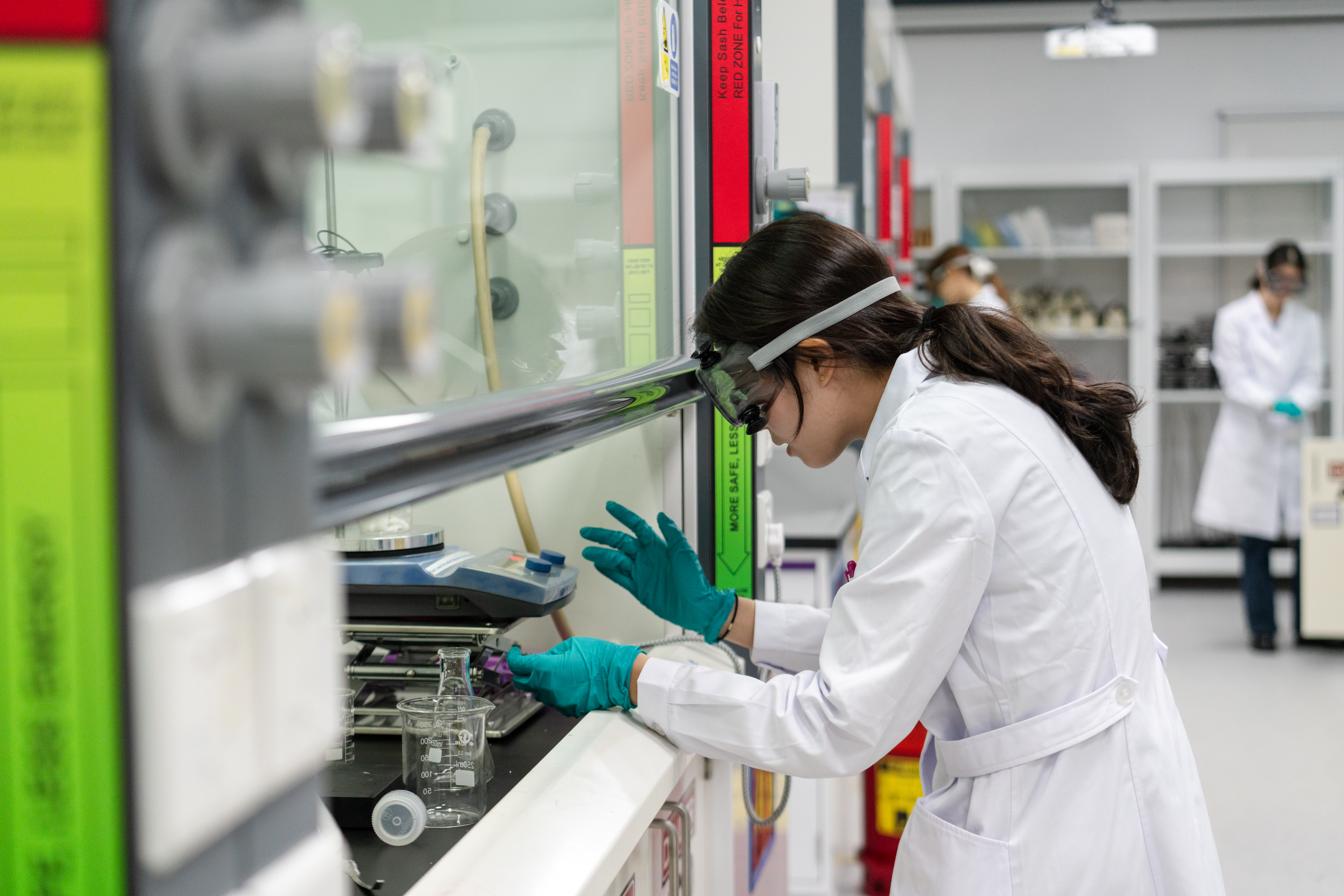 A student in safety gear working in a lab.