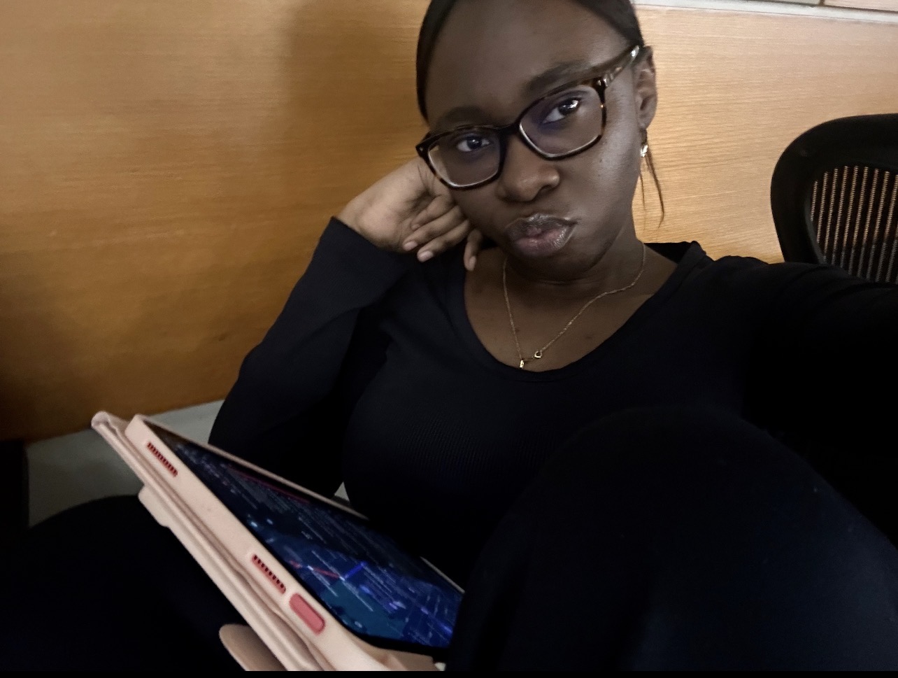 student in the library with a pink ipad in her lap
