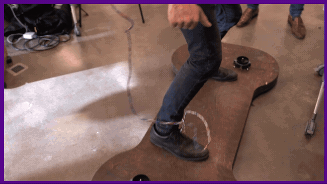 A student rides on a board prototype with the assistance of another student.