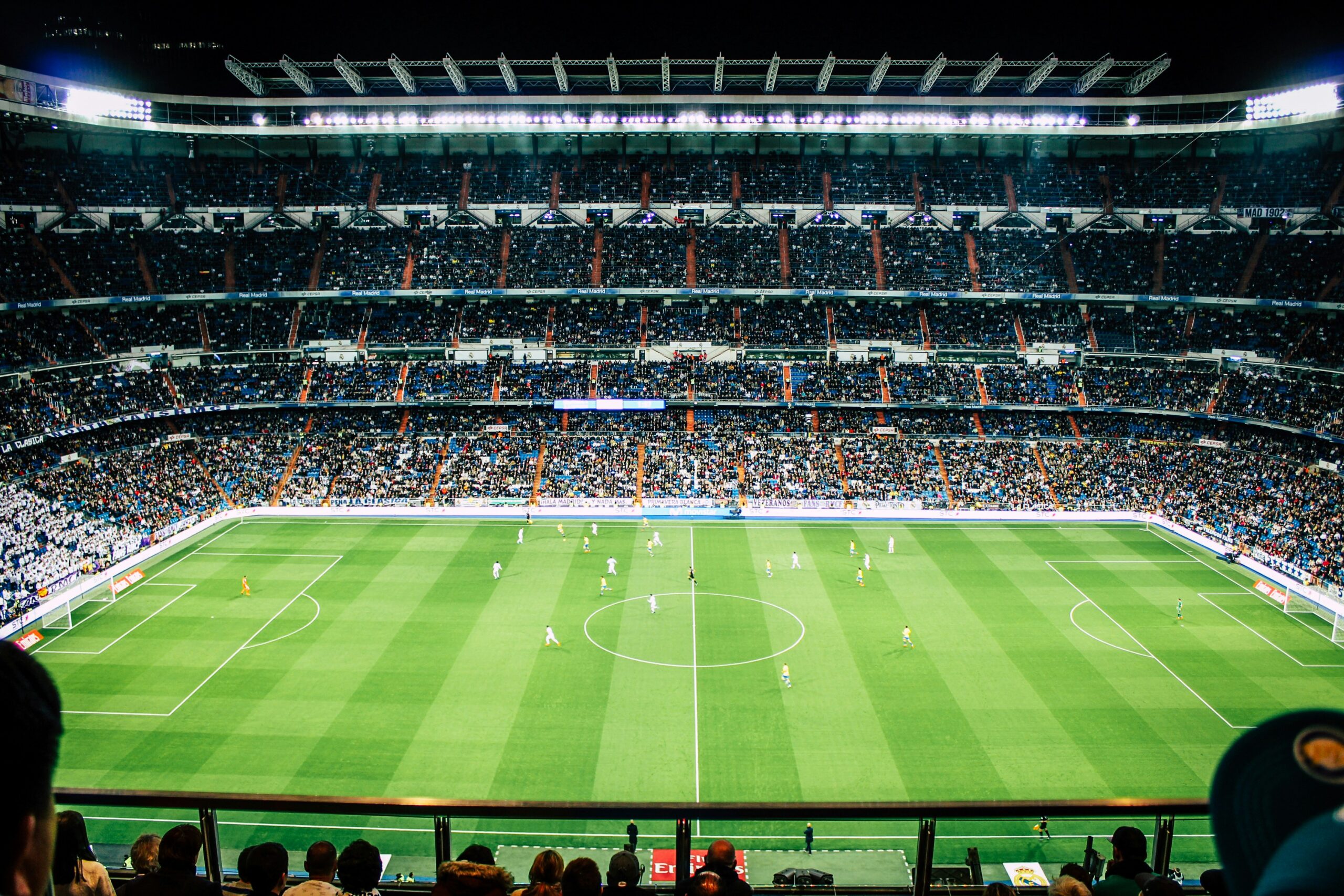 Soccer teams play in front of a crowded stadium.