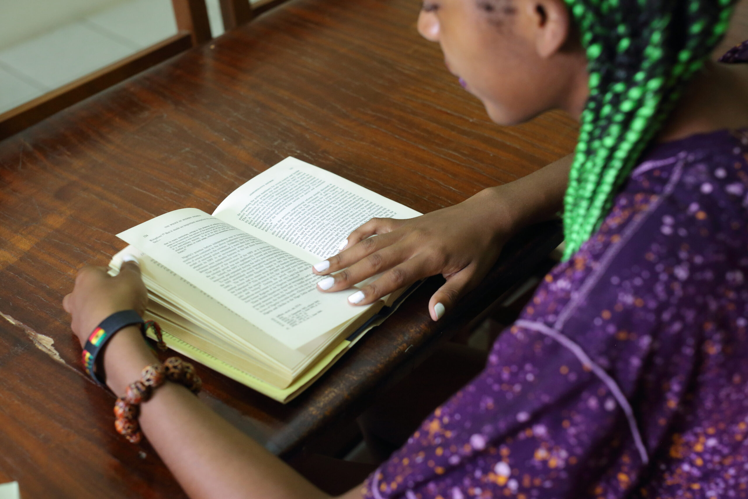 A student reading a book while seated in a library.
