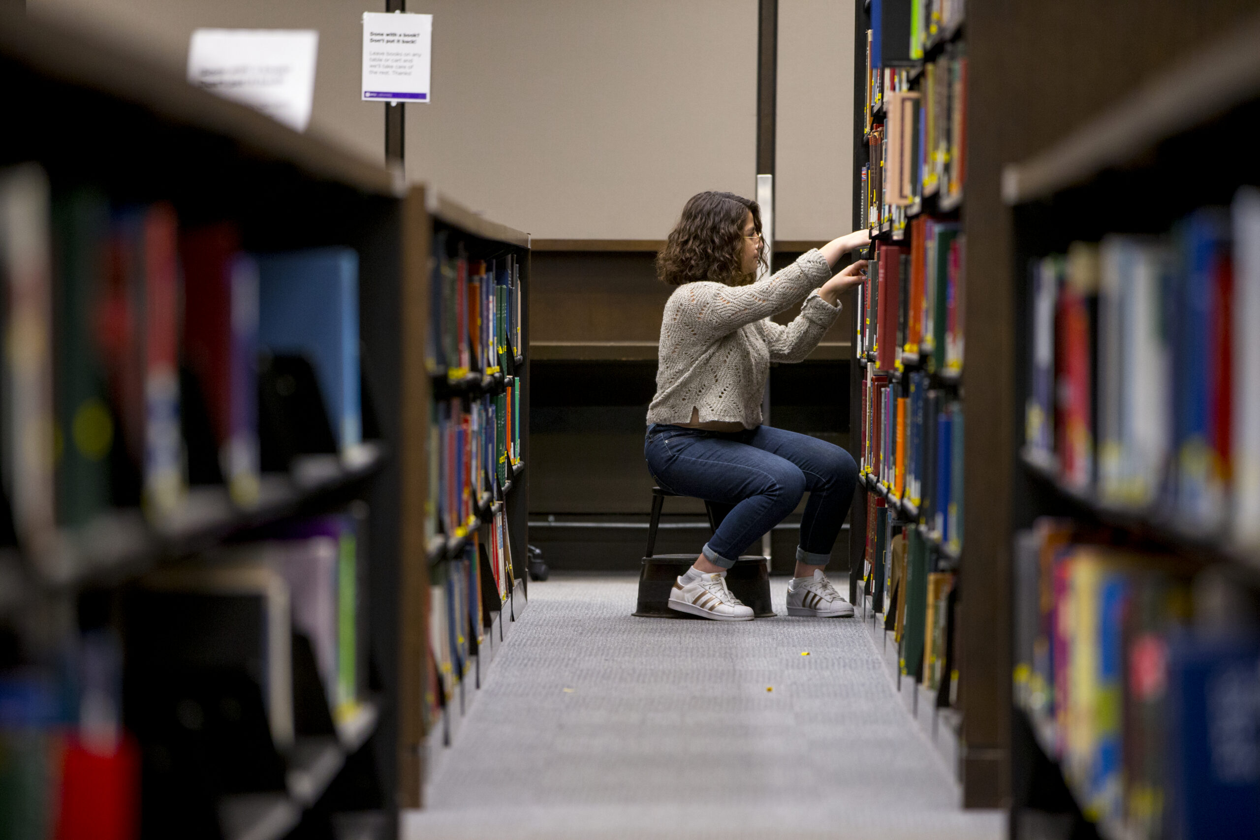 A student searching through the library stacks.
