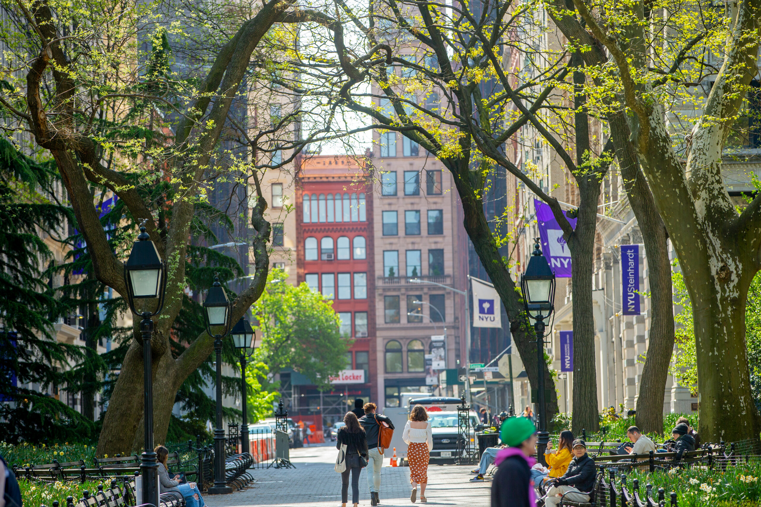 People walking around Washington Square park on a clear bright day