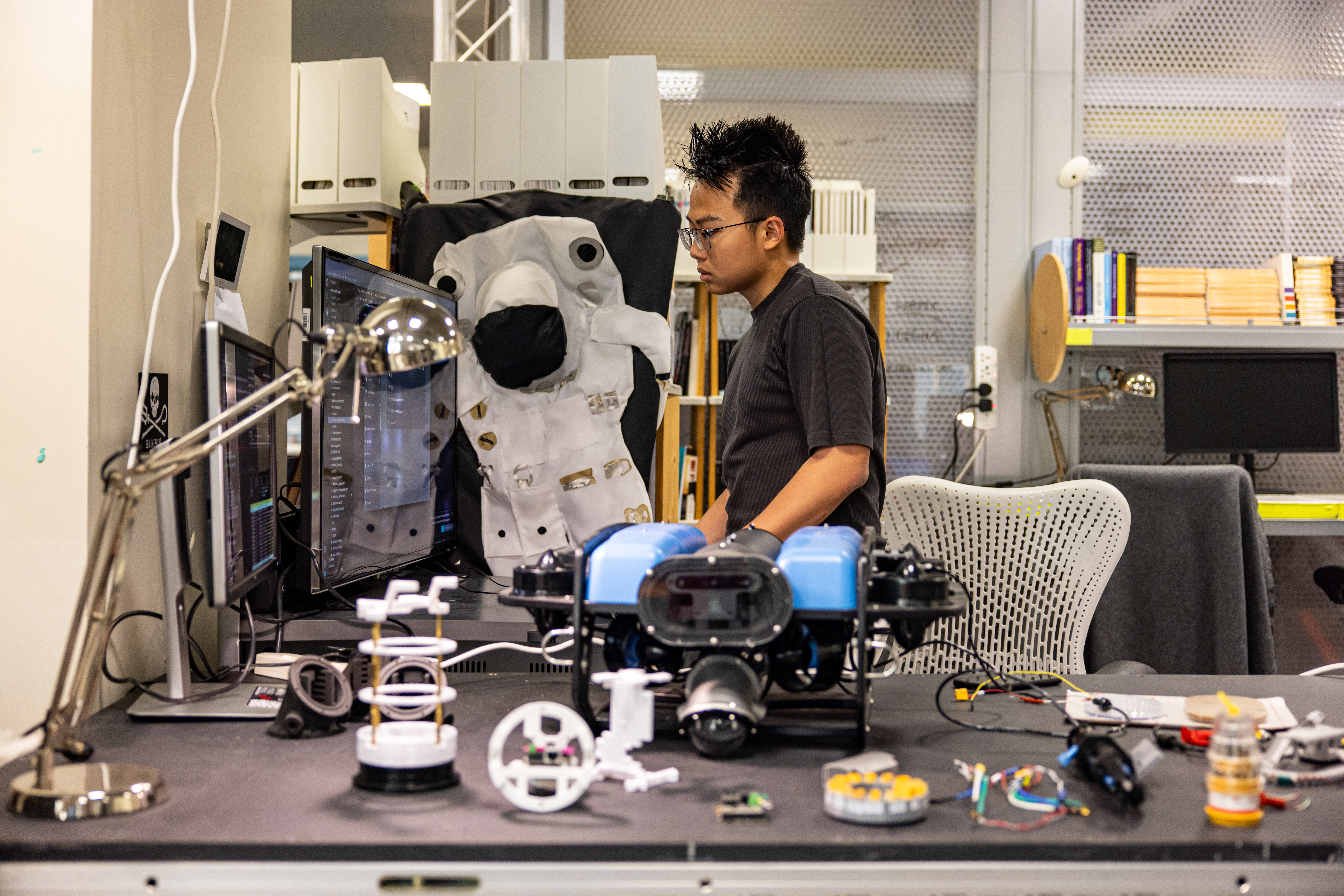 A student working on their engineering project on a computer surrounded by equipment