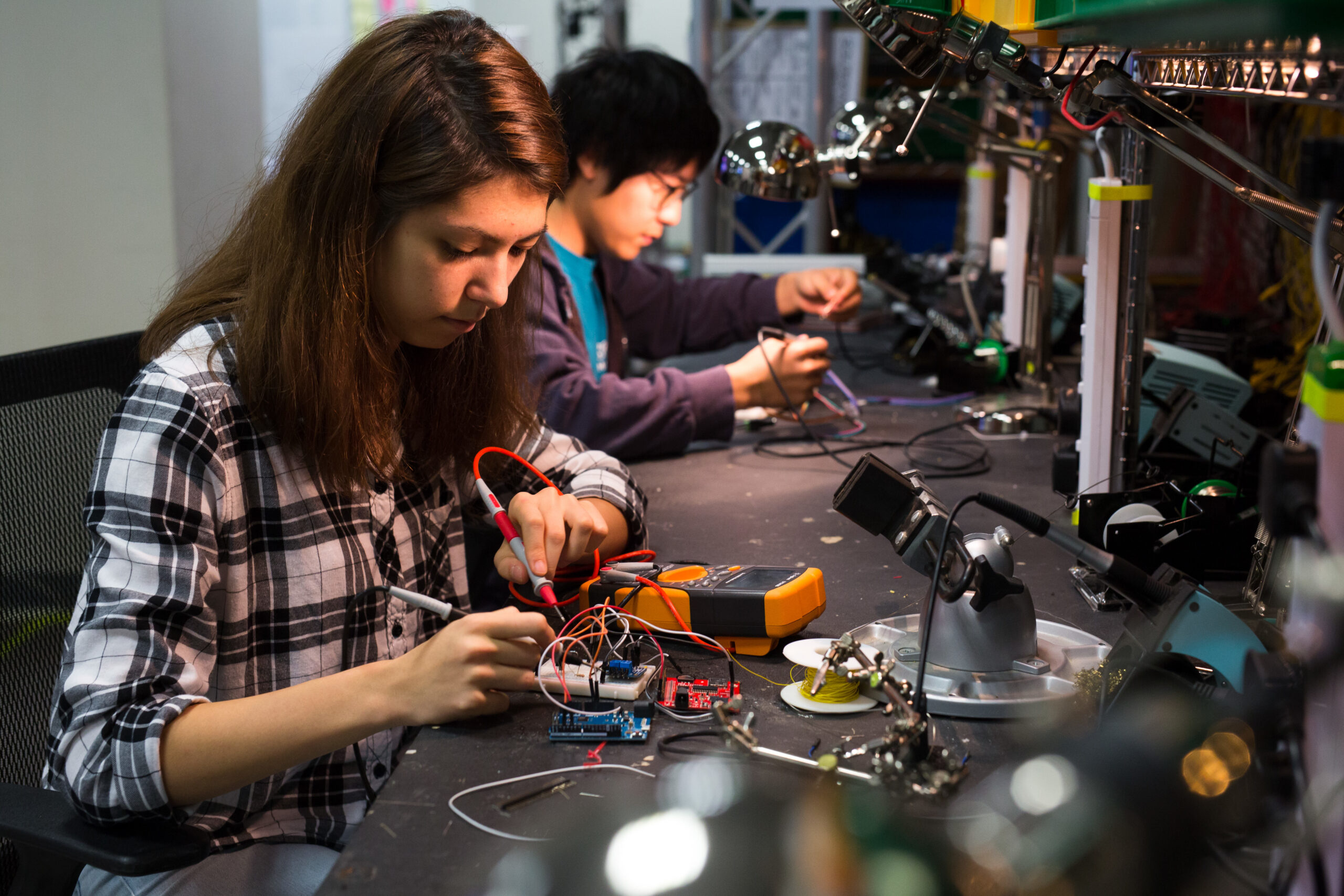 Two students working on their engineering projects in a workspace